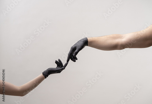 Hands in black silicone gloves stretches to each other to touch