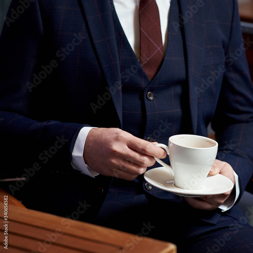 Business style. Men style. Businessman in a blue jacket with a cup of coffee