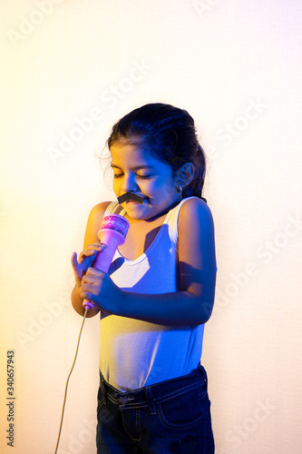 Little girl with a mustache singing using her microphone