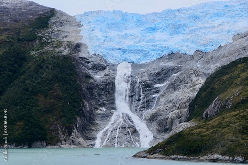 Glacier with waterfall in chilean fjord  blue ice and clouds  glacier alley  Beagle Channel