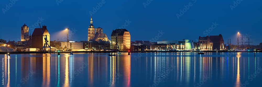 Stralsund, Germany. Panoramic view of the North Harbor in dusk with St. James Church (left), St. Nicholas Church (center), historical warehouses (right).