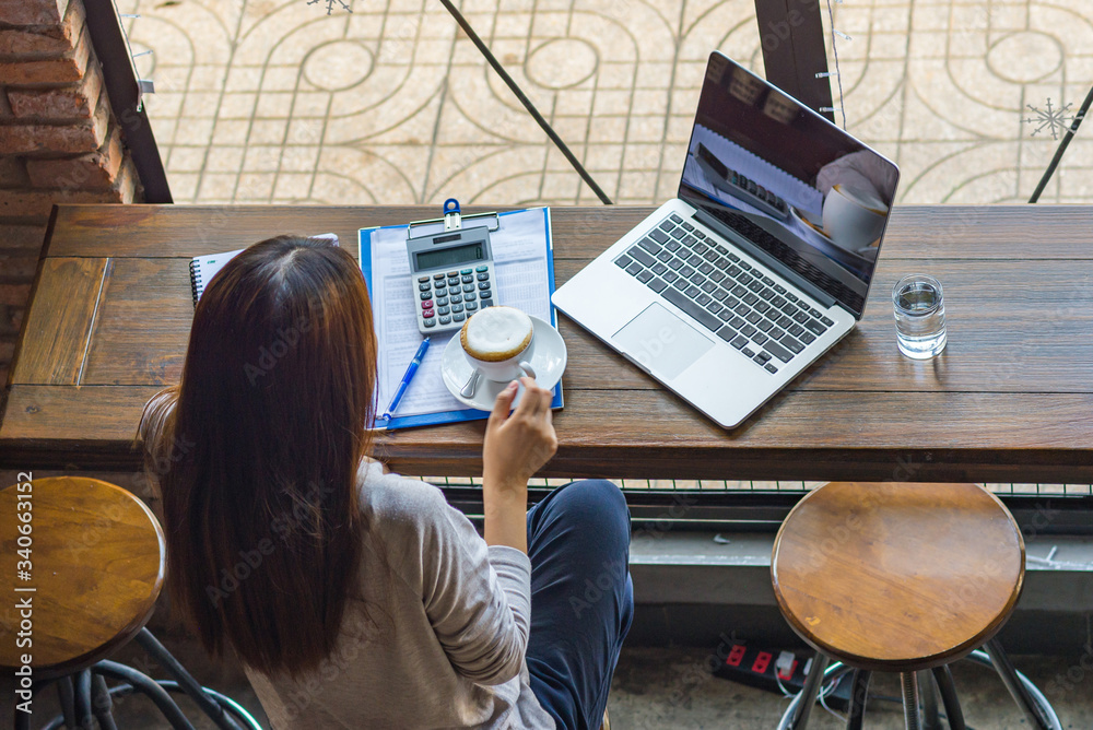 Fototapeta premium Asian freelancer drinking hot cup of coffee at the rustic cafe