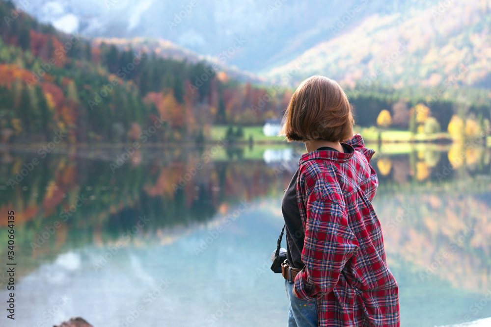 girl stands on the shore of a mountain lake