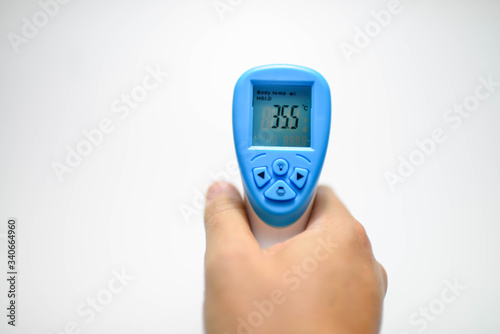Hand holding Digital Infrared Thermometer (thermometer gun) for check forehead temperature measurement scan from Coronavirus Disease 2019 (COVID-19)