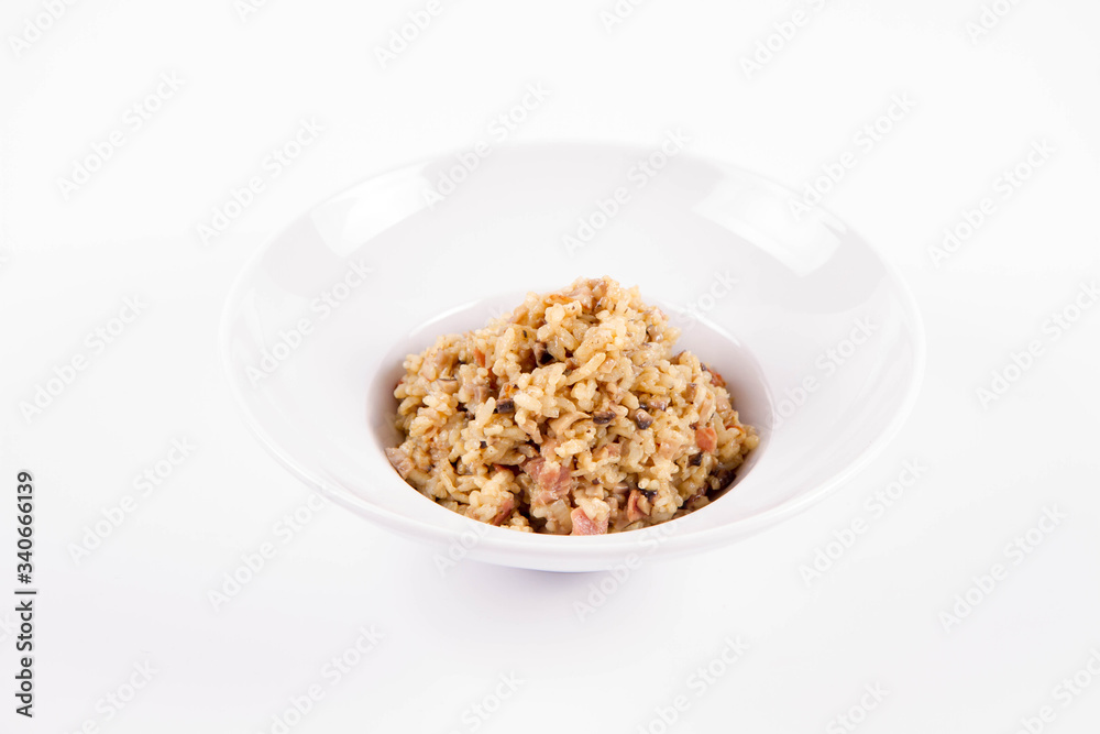 Risotto with button mushroom and bacon on a plate on a white background Risotto with button mushroom and bacon on a plate on a white background