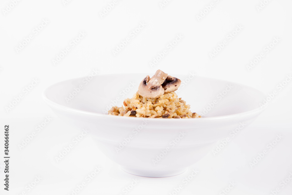 Risotto with button mushroom and bacon decorated with mushroom on a plate on a white background Risotto with button mushroom and bacon decorated with mushroom on a plate on a white background