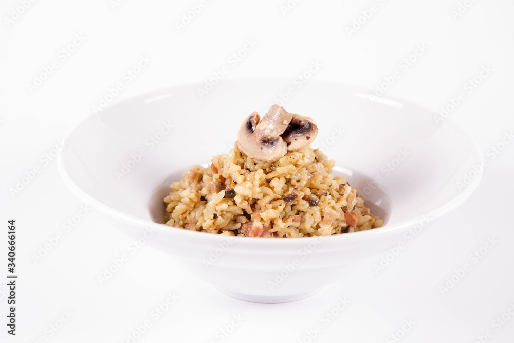 Risotto with button mushroom and bacon decorated with mushroom on a plate on a white background Risotto with button mushroom and bacon decorated with mushroom on a plate on a white background
