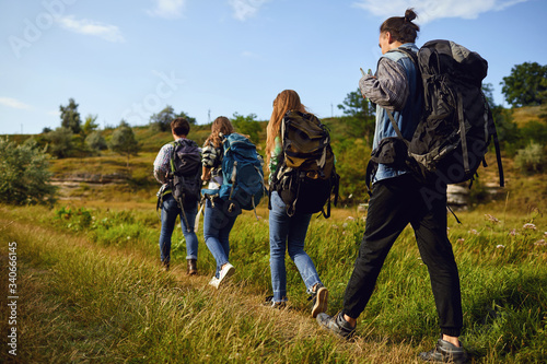 A group of tourists with backpacks is walking in nature