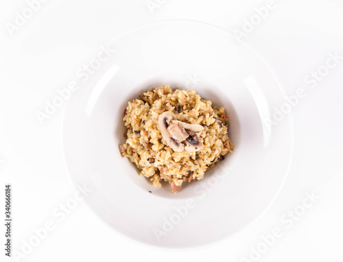 Risotto with button mushroom and bacon decorated with mushroom on a plate on a white background