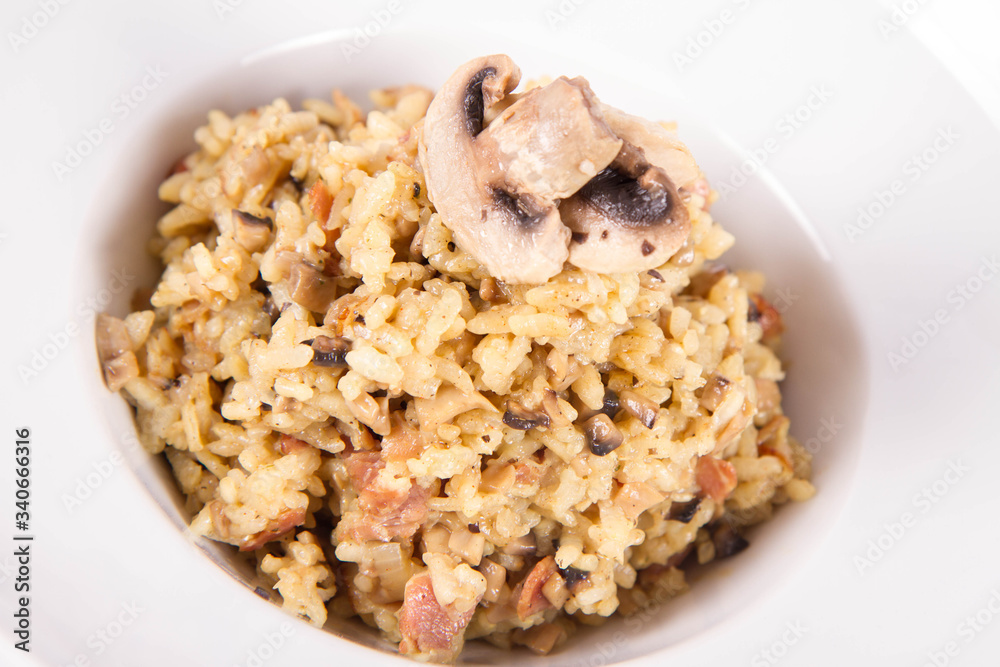 Risotto with button mushroom and bacon decorated with mushroom on a plate on a white background Risotto with button mushroom and bacon decorated with mushroom on a plate on a white background