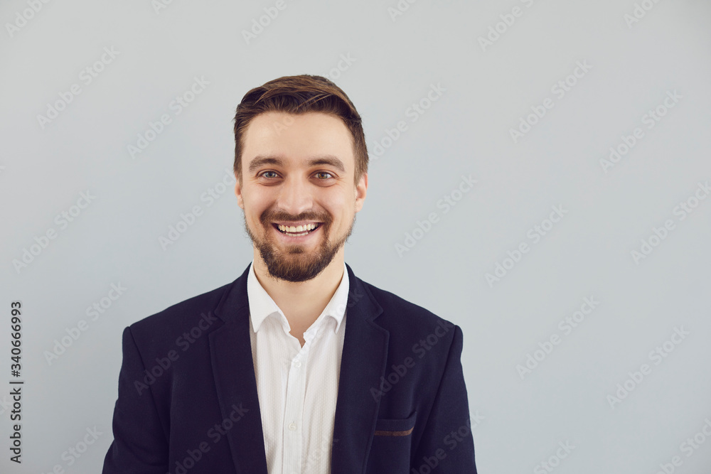 Positive bearded guy in a jacket smiling looks at the camera on a gray background. Positive bearded guy in a jacket smiling looks at the camera on a gray background.