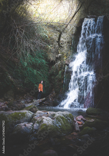 woman with orange shirt in a waterfall in the forest photo