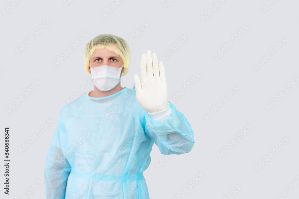 Doctor hand makes a stop sign. White protective gloves. Medical mask on the face. Surgeon in working uniform. No to viruses and diseases. A gesture requiring stopping. Epidemic Landing Page. Doctor hand makes a stop sign. White protective gloves. Medical mask on the face. Surgeon in working uniform. No to viruses and diseases. A gesture requiring stopping. Epidemic Landing Page.