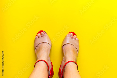 female legs and summer open toes shoes on colorful background. Yellow background, free copy space. Overhead shot of elegant shoes of pastel color. Top view
