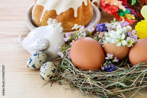Traditional Easter decoration with eggs, hay and flowers.