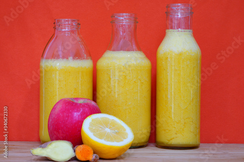 Glass bottles filled with colorful fresh homemade apple, lemon and ginger smoothies