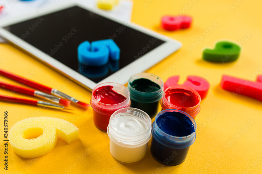 school paint supplies and tablet on a yellow isolated background, theme back to school school paint supplies and tablet on a yellow isolated background, theme back to school