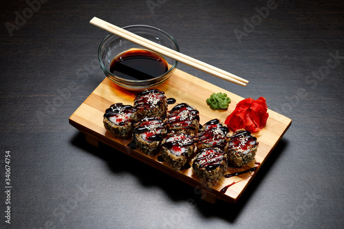 Tasty and delicious hot and cold sushi rolls on the table. Different sushi - rolls with sauce on the board of Japanese cuisine. photo