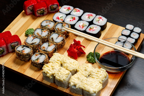 Tasty and delicious hot and cold sushi rolls on the table. Different sushi - rolls with sauce on the board of Japanese cuisine. photo