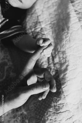 Newborn holds mom's finger close-up.