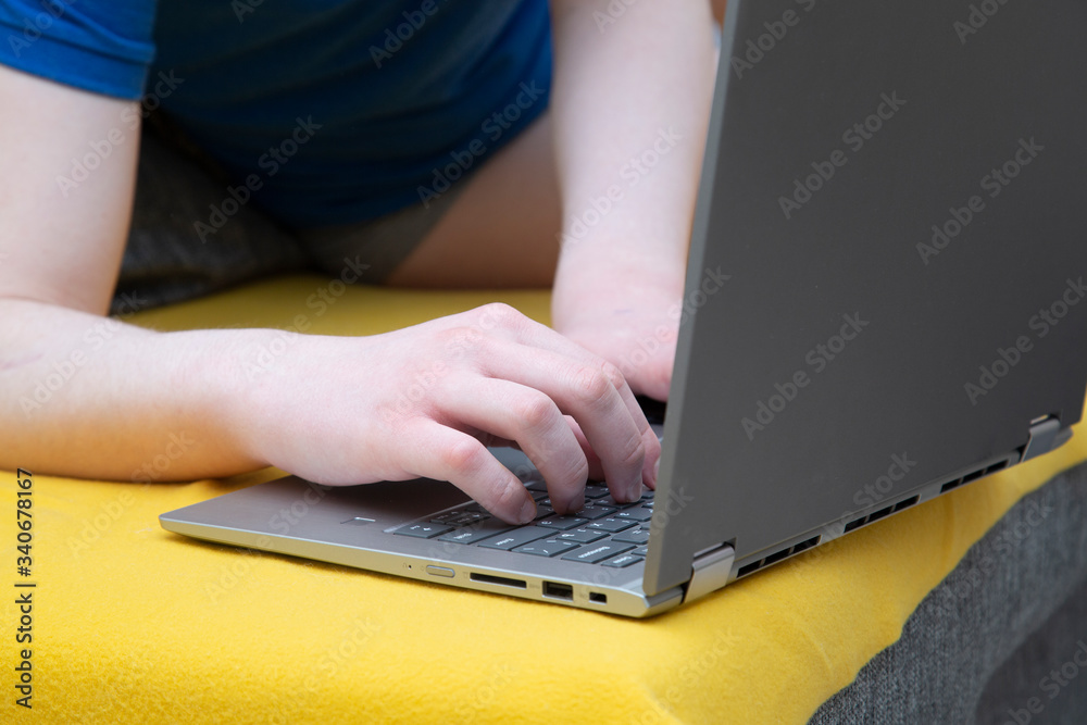 Fototapeta premium A man is sitting on the sofa at a laptop. Engaged in work on deleting over the Internet.