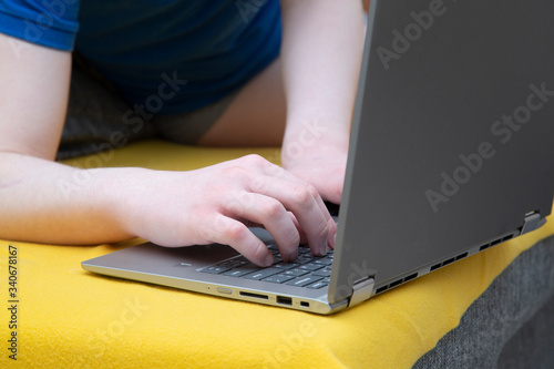 A man is sitting on the sofa at a laptop. Engaged in work on deleting over the Internet.