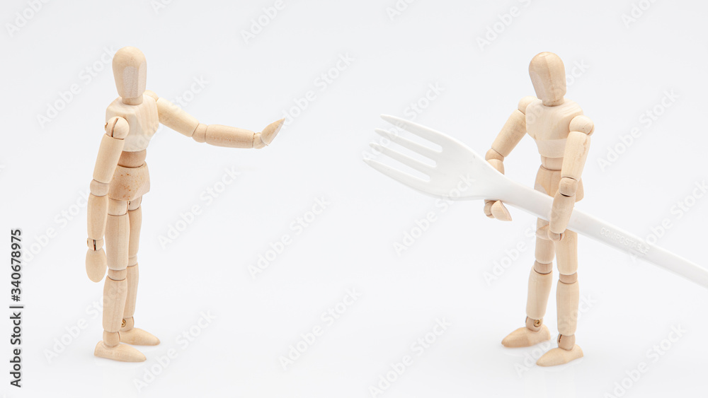 Wooden dummy refusing to help his friend to carry a biodegradable fork in front of a white background Wooden dummy refusing to help his friend to carry a biodegradable fork in front of a white background