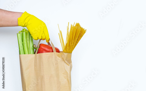 Coronavirus food supplies concept. Brown paper bag with vagetables and pasta isolated on a white background. Copy space