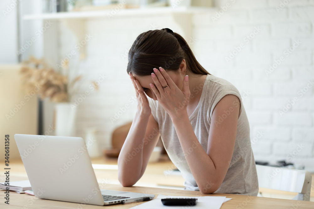 Upset woman touching head using calculator and laptop for calculating finance. Frustration young housewife with headache taxing, accounting, statistics and credit analytic for mortgage payment. Upset woman touching head using calculator and laptop for calculating finance. Frustration young housewife with headache taxing, accounting, statistics and credit analytic for mortgage payment.