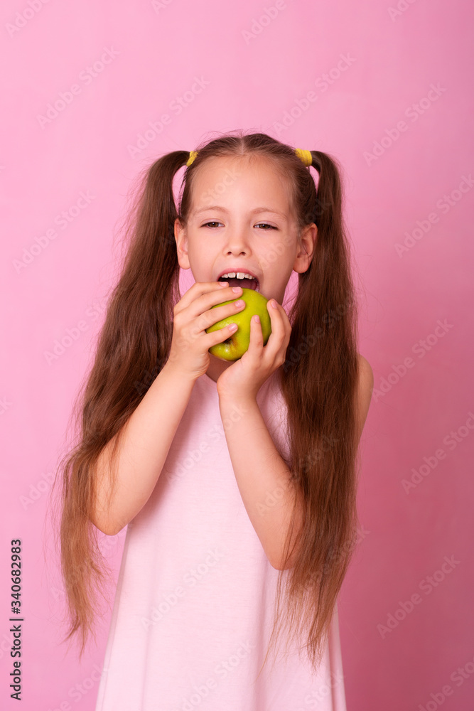 A beautiful portrait of a little girl who eats a green apple. A beautiful portrait of a little girl who eats a green apple.