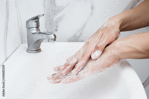 Young man washing hands over sink in bathroom, closeup, Corona virus or Covid-19 prevention, hygiene to stop.