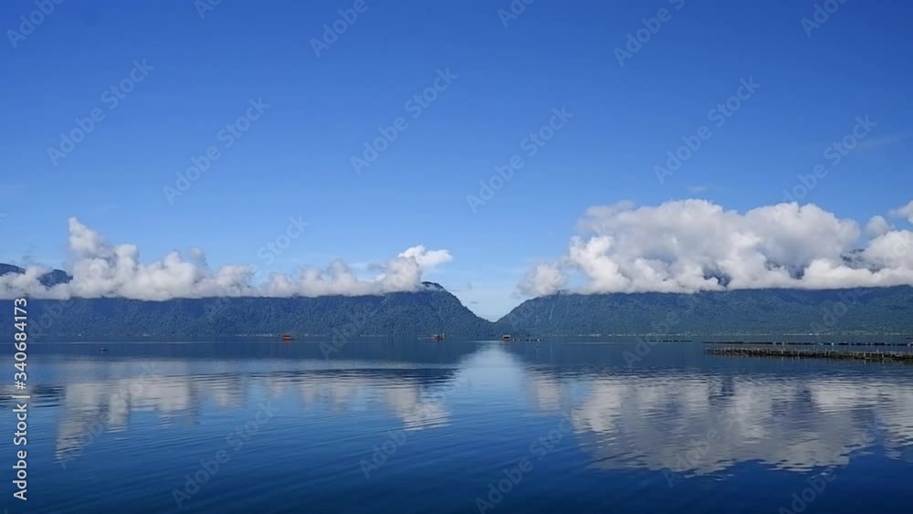 Beautiful landscape view of blue lake with blue hill and bright clouds. Photographed in lake Maninjau, West Sumatra, Indonesia. Beautiful landscape view of blue lake with blue hill and bright clouds. Photographed in lake Maninjau, West Sumatra, Indonesia.