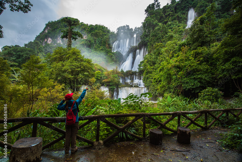 The girl in blue sweater touring on Thi-Lo-Su waterfall, Beautiful waterfall in Tak  province, ThaiLand.