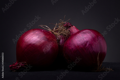 Purplish vibrant red onions studio low key still life against a dark grey background