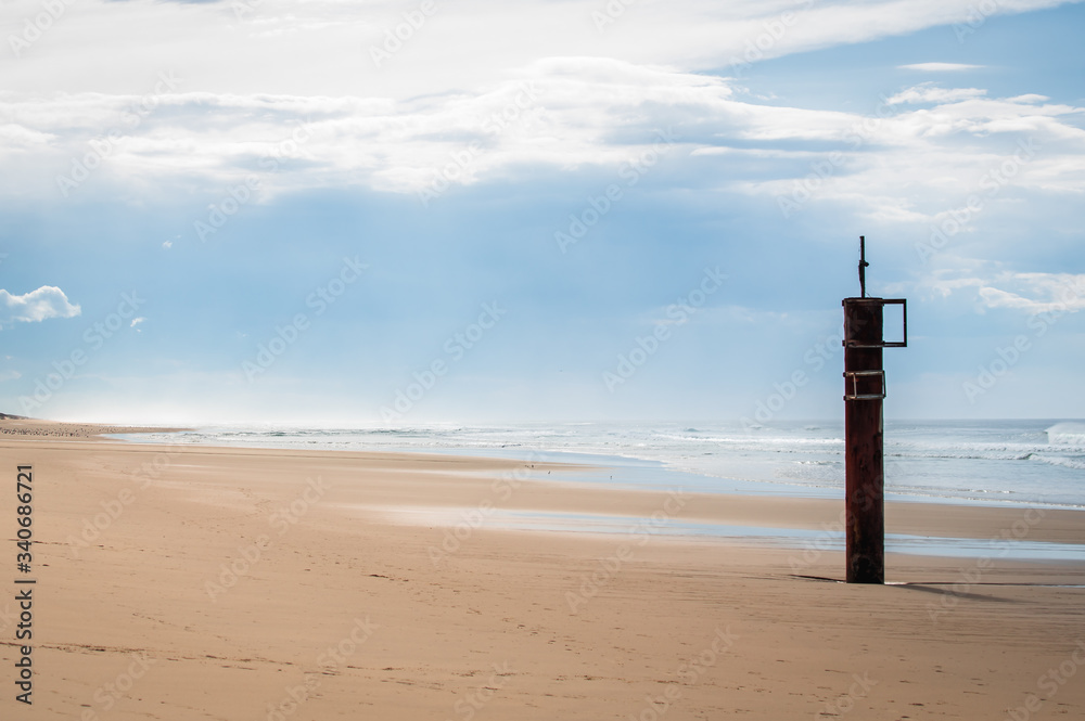 Pylône esseulé sur la plage en bord d'océan un jour de grisaille