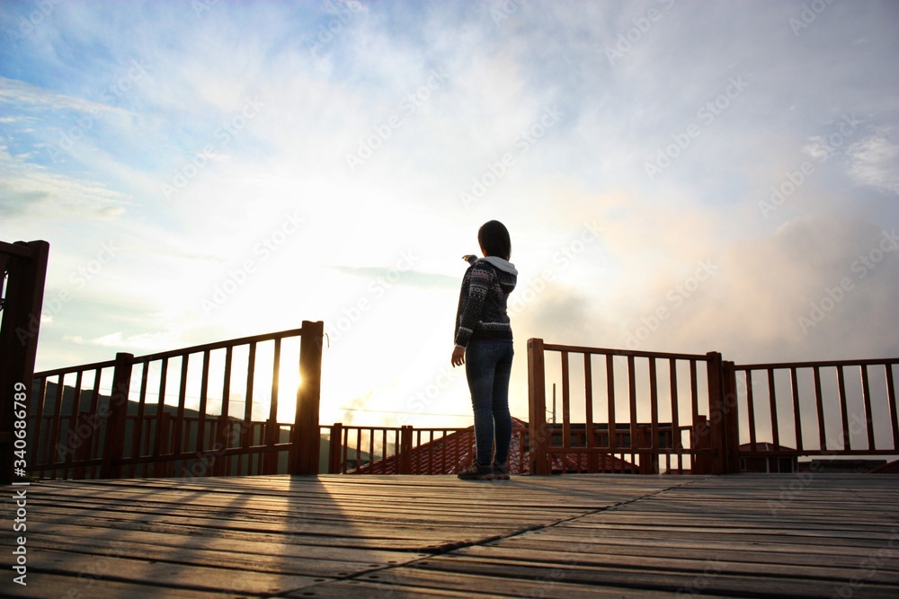 Fototapeta premium chica mirando el atardecer señalando el sol