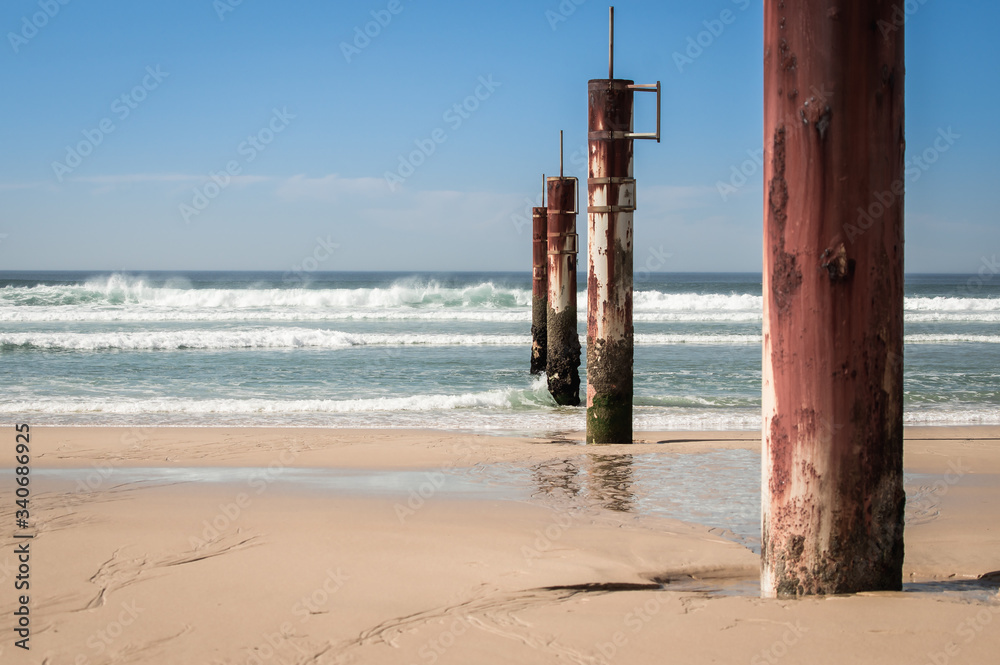 Pylônes rouillés sur la plage au bord de l'océan en été