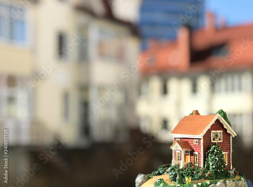 small realistic-look toy house outdoors with cottages on background