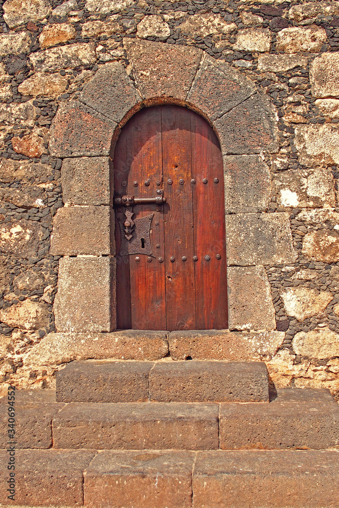  old wooden door with metal fittings in a stone building creating a background with stairs