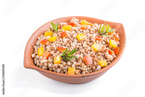 Buckwheat porridge with vegetables in clay bowl isolated on white background. Side view, close up.