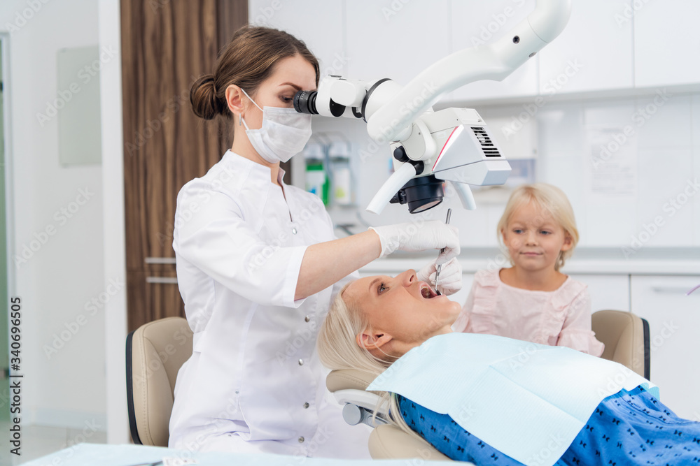 Obraz premium A dentist examines the oral cavity of her patient on the dentist's chair with the help of a special medical appliance