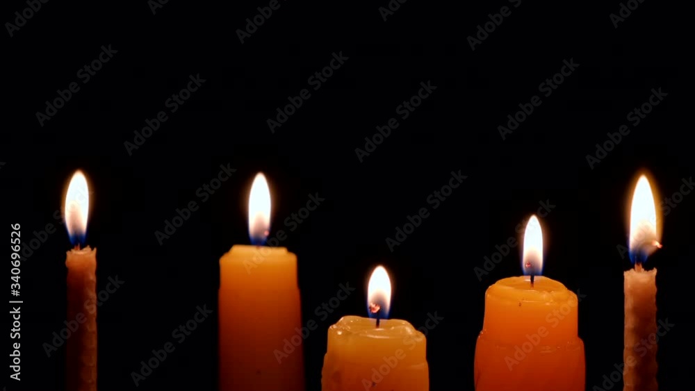 Candles burning on black background. Candle flame isolated on black background. Flames sway in the wind from the draft. Closeup, macro, close-up Candles burning on black background. Candle flame isolated on black background. Flames sway in the wind from the draft. Closeup, macro, close-up
