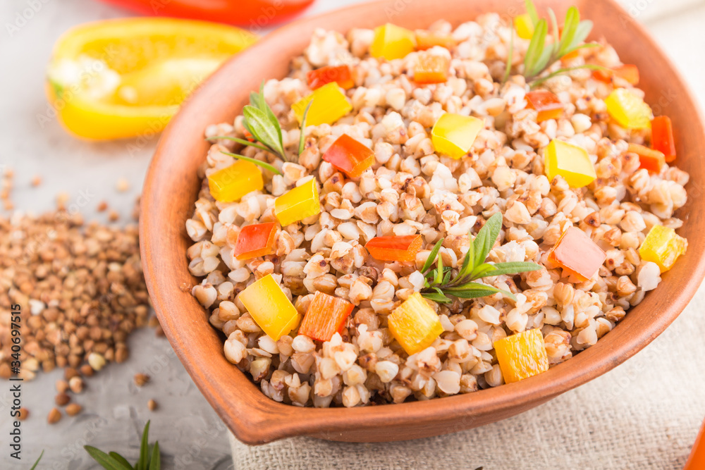 Buckwheat porridge with vegetables in clay bowl on a gray concrete background and linen textile. Side view, close up, selective focus. Buckwheat porridge with vegetables in clay bowl on a gray concrete background and linen textile. Side view, close up, selective focus.