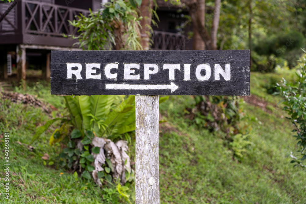 Text reception on a wooden board near tropical hotel in Borneo, Malaysia. Reception wooden sign inscription in the asian tropics Text reception on a wooden board near tropical hotel in Borneo, Malaysia. Reception wooden sign inscription in the asian tropics