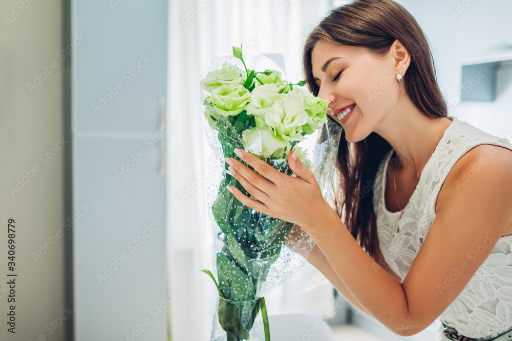 Woman smelling bouquet of eustoma flowers. Housewife enjoying decor and interior of kitchen on quarantine. Sweet home Woman smelling bouquet of eustoma flowers. Housewife enjoying decor and interior of kitchen on quarantine. Sweet home