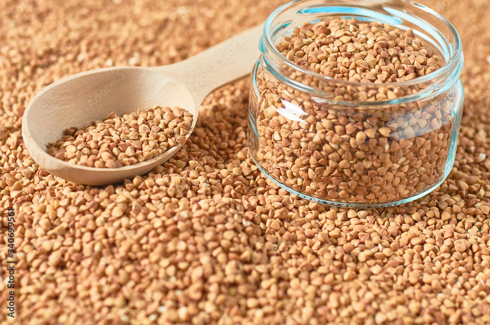Full wooden spoon and glass jar of grains of buckwheat. Agricultural concept Full wooden spoon and glass jar of grains of buckwheat. Agricultural concept
