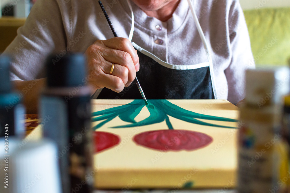 Fototapeta premium Front view of old woman painting a picture at home. Art in the elderly and leisure at home.