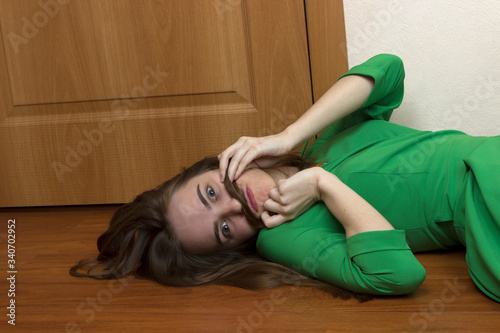 Canvastavla A beautiful long-haired blonde girl is fooling around, lying on the floor near t