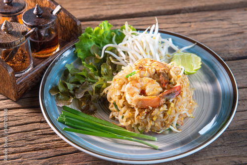 Phad Thai with fresh shrimp  add eggs  served with lettuce  bean sprouts  spring onions  with garnish arrange a beautiful dish  put on a wooden table.