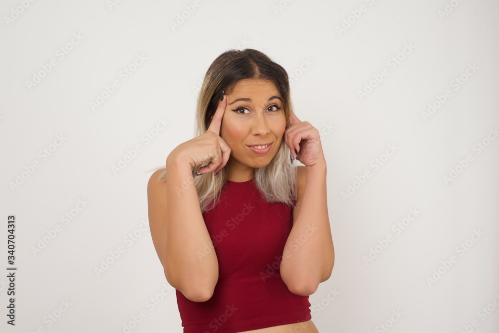 Young beautiful girl concentrating hard on an idea, with a serious look, thinking with both index fingers pointing to forehead eyes closed. Young beautiful girl concentrating hard on an idea, with a serious look, thinking with both index fingers pointing to forehead eyes closed.